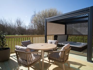 An outdoor seating area with a table and chairs beside a hot tub at The Luxury Hideaway in Waltham