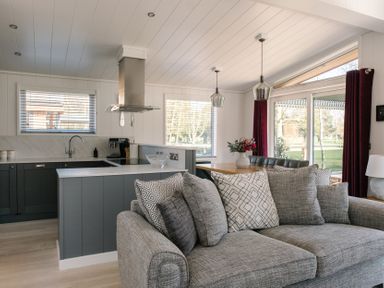 A living room with a sofa and kitchen counter at The Luxury Hideaway in Waltham