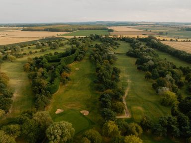 A golf course surrounded by trees and fields at The Royal in Waltham