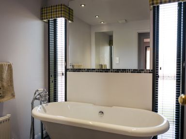 A bathroom with a bathtub and mirror at Macosi in Waltham