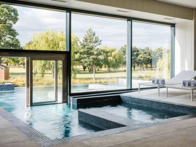 An indoor pool with large windows overlooking a green area at Macosi in Waltham