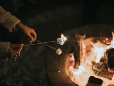 A person roasting marshmallows over a fire pit at Macosi in Waltham