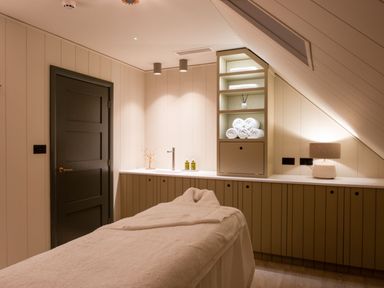 A spa room with a massage table and shelves at Macosi in Waltham