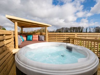 A hot tub with cushions on a wooden deck at Luxury Boutique Retreat Pet in Waltham