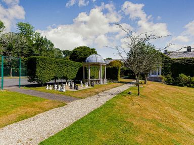 A garden with a gazebo and chess set at Aubyn Lodge Spa in Praze-An-Beeble