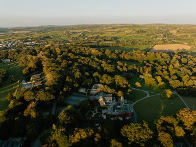 An aerial view of a landscape with trees and a house at Aubyn Lodge Spa in Praze-An-Beeble