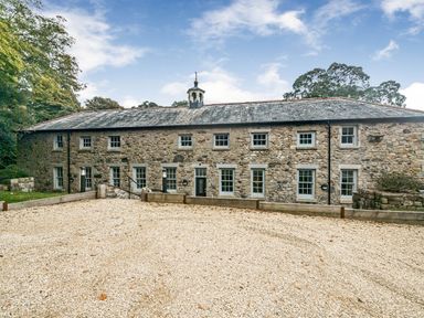 A stone building with windows and a gravel driveway at Coach House in Praze-An-Beeble
