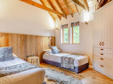 A bedroom with two beds and a wardrobe at The Treehouse in Praze-An-Beeble