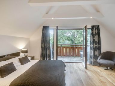 A bedroom with a bed and sliding doors to a balcony at Cornwall Lodge Spa in Praze-An-Beeble