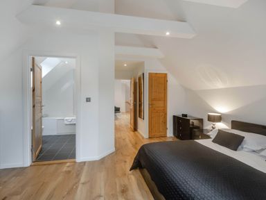 A bedroom with bed, nightstand, and an en-suite bathroom at Cornwall Lodge Spa in Praze-An-Beeble