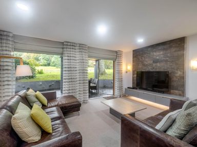A living room with a sofa and television at St Austell Lodge Spa in Praze-An-Beeble