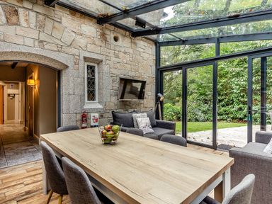 A conservatory with a dining table and chairs at The Gatehouse in Praze-An-Beeble