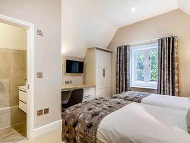 A bedroom with twin beds and a desk at The Gatehouse in Praze-An-Beeble