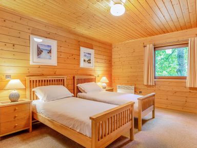 A bedroom with two single beds and a nightstand at Woodland Lodge Spa Praze-An-Beeble