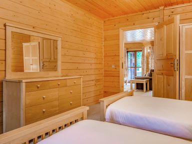 A bedroom with a dresser and two beds at Woodland Lodge Spa in Praze-An-Beeble
