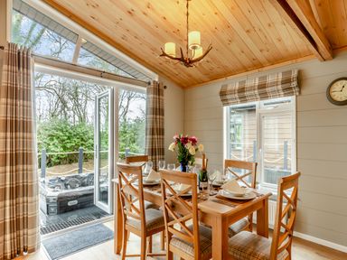 A dining room with a table set for dinner and a view of a hot tub at Argel Spa Pet in Praze-An-Beeble
