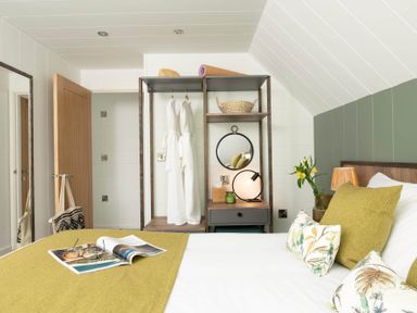 A bedroom with a bed and shelf containing decorative items at Kilden Pet in Praze-An-Beeble