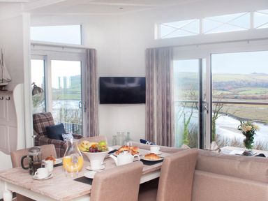 A living room with a dining table and view of the river at Milk Wood 2 Spa in Laugharne
