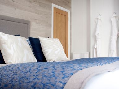 A bedroom with a bed and decorative pillows at Milk Wood 2 Spa Laugharne