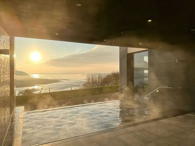 A spa area with hot tub and a view of the sun over a coastline at Sonnet 2 Spa in Laugharne