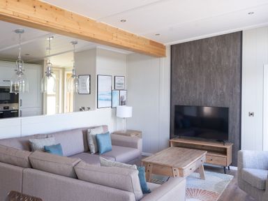 A living room with a sofa and television at Milk Wood 3 Spa in Laugharne