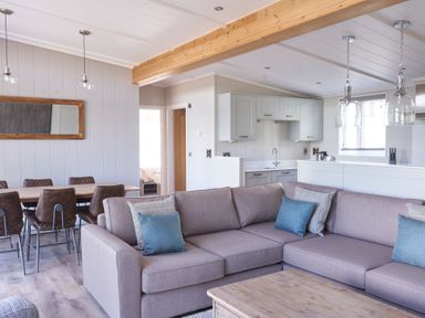 A living room with a sofa and dining table at Milk Wood 3 Spa in Laugharne