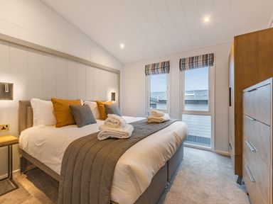 A bedroom with a bed and windows at Apex Spa Laugharne