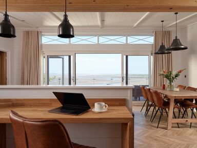 A dining room with a wooden table and laptop at Canto Spa in Laugharne