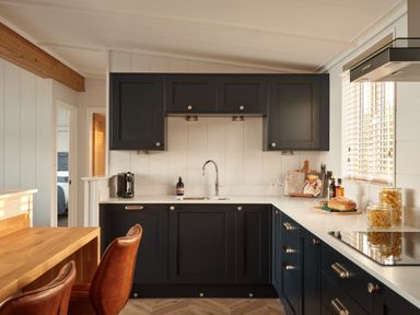 A kitchen with dark cabinets and countertop at Canto Spa in Laugharne