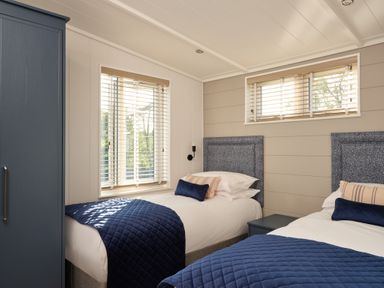 A bedroom with two beds and a wardrobe at Canto Spa, Laugharne