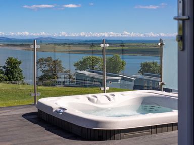 A hot tub with a view of a lake at Apex Spa (Pet) Laugharne