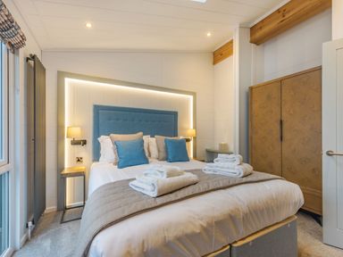 A bedroom with a bed and wardrobe at Apex Spa (Pet) in Laugharne