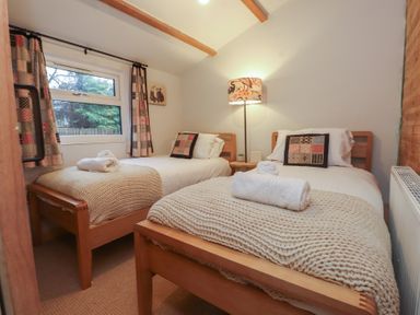 A bedroom with two beds and a lamp at 20 Chatham Log Cabins in Caernarfon