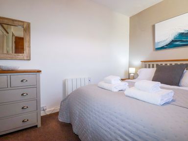 A bedroom with a bed and towels arranged at Chapel Cottage, Mevagissey
