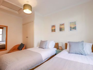 A bedroom with two beds and paintings on the wall at Chapel Cottage in Mevagissey