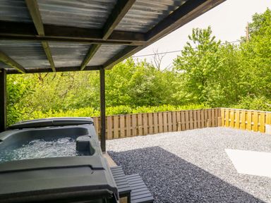 An outdoor area with a jacuzzi and gravel surface at Lodge at Nadur Commins Coch near Machynlleth