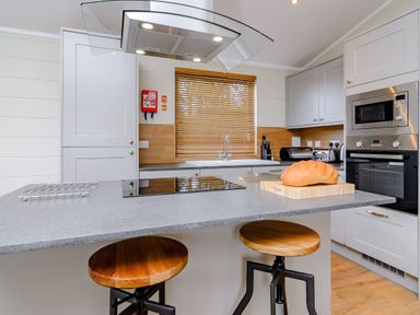 A kitchen with an island and stools at The Folkesworth in Kings Cliffe