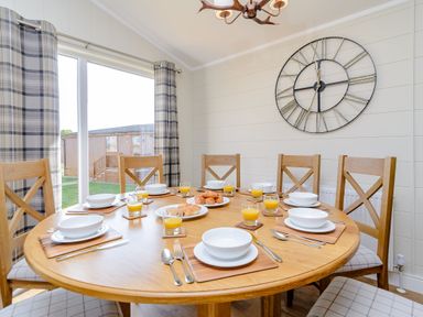 A dining room with a round table set with plates and orange juice at The Folkesworth (Pet) Kings Cliffe