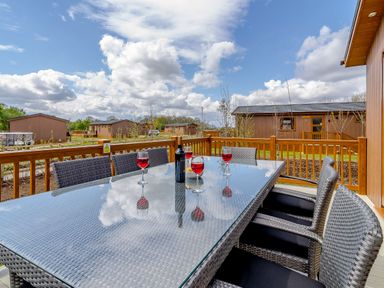 An outdoor seating area with a table and wine glasses at The Alwalton (Pet) Kings Cliffe