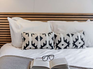 A bed with pillows and a book with glasses on top at Saron 2.0 Pet in Llandyrnog