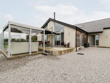 An outdoor area with seating and a glass enclosure at Cae Sam in Pentraeth