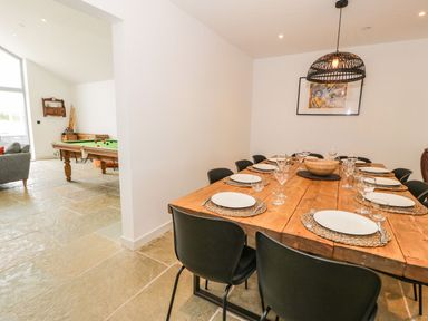 A dining room with a large table set for dinner and a pool table at Cae Sam in Pentraeth