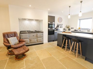 A kitchen with a stove and bar stools at Cae Sam in Pentraeth