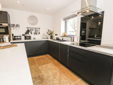 A kitchen with dark cabinets and a sink at Cae Sam in Pentraeth