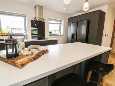 A kitchen with a kitchen island and stools at Cae Sam in Pentraeth
