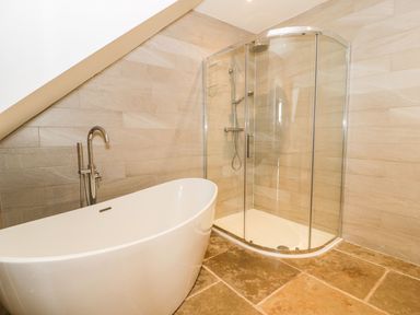 A bathroom with a bathtub and shower at Cae Sam Pentraeth