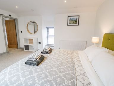 A bedroom with a bed, towels, lamp, and shelf at Cae Sam in Pentraeth