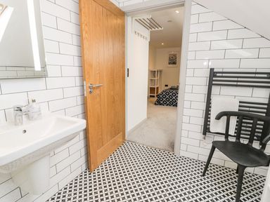 A bathroom with a sink and door at Cae Sam Pentraeth