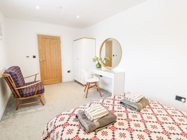 A bedroom with a bed and mirror at Cae Sam in Pentraeth