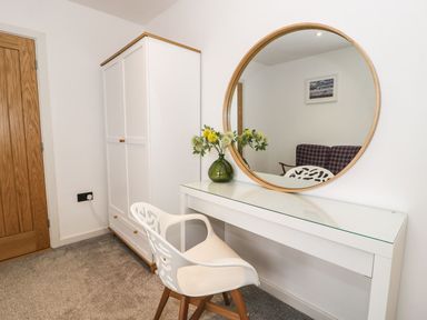 A bedroom with a mirror and table at Cae Sam in Pentraeth